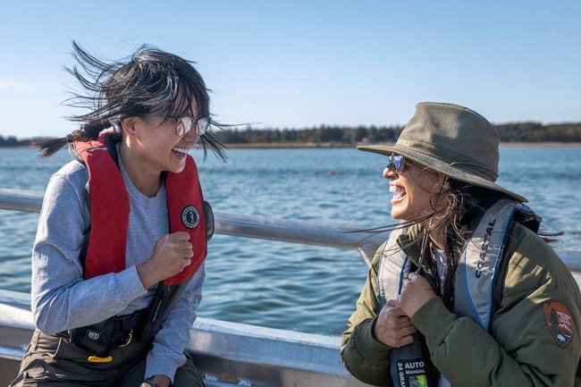 Two smiling park rangers on a boat in the Atlantic.