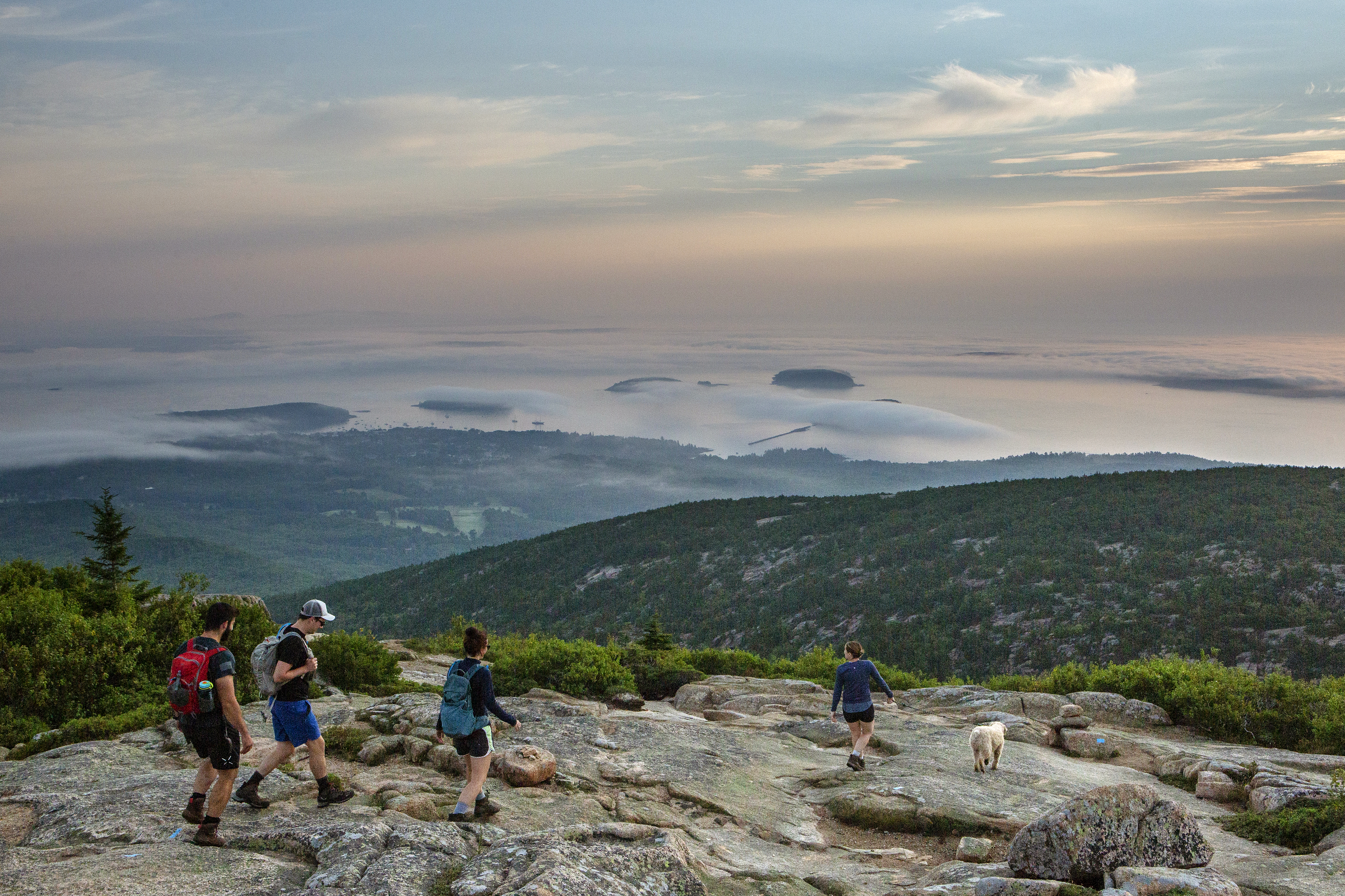 Visitors watch as the rising sun illuminates foggy Porcupine Islands from Cadillac Mountain in Acadia National Park