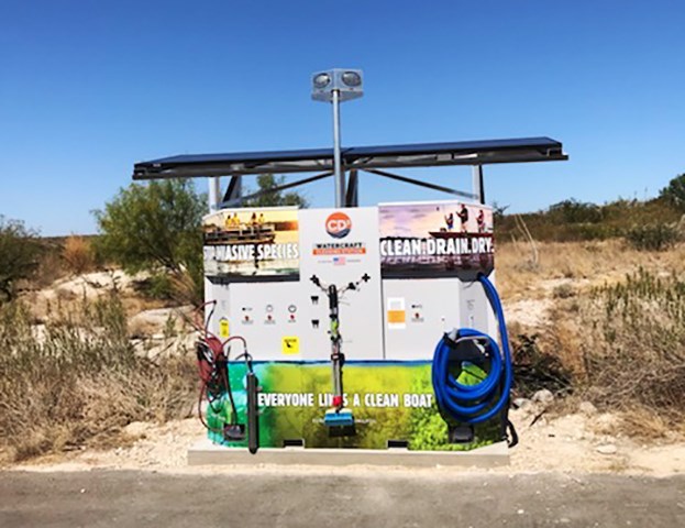 Permanently mounted AIS CD3 unit with hoses lights and ads with statements "Stop Invasive Species," "Clean. Drain. Dry.", and "Everyone Likes a Clean Boat" on attached panels.