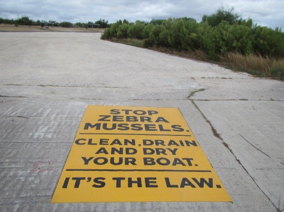Boat Ramp stencil about aquatic invasives stating "Stop Zebra Mussels. Clean, drain, and dry your boat. It's the law."