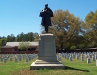 Stone and Bronze monument of a Civil War soldier surrounded by white headstones