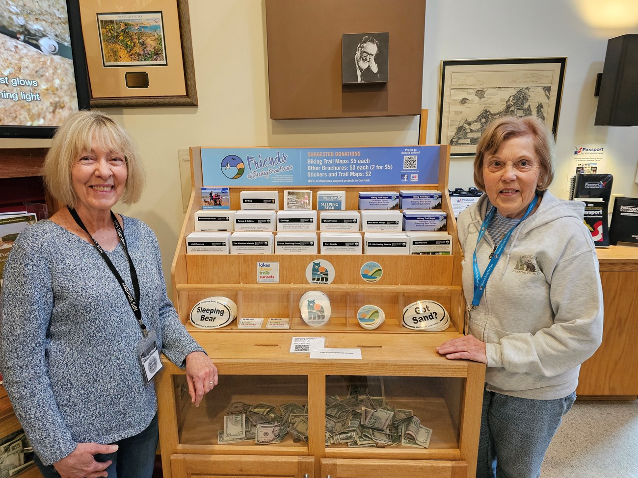 Two volunteers standing next to a donation display with books and stickers.