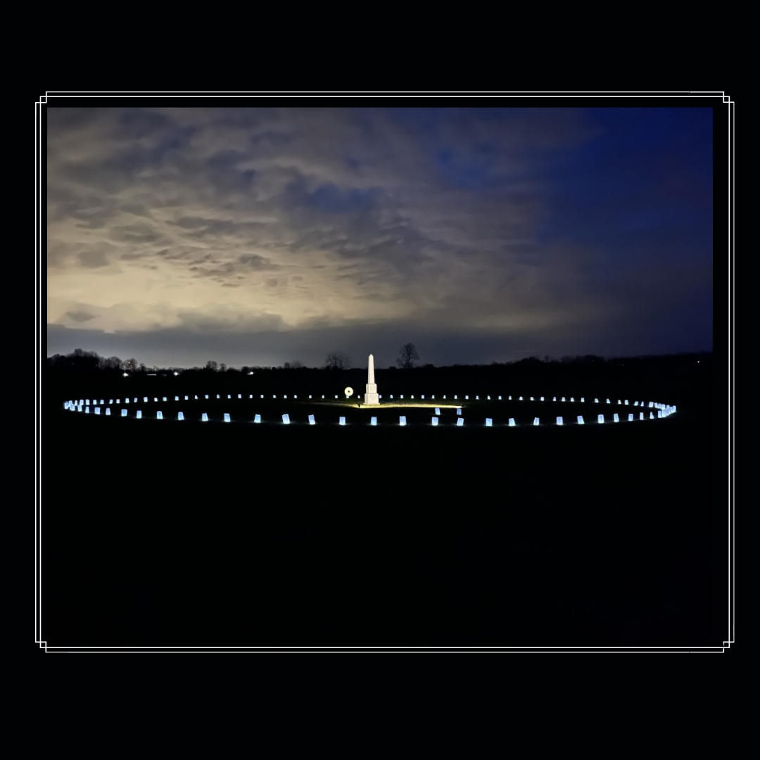 A modern photograph of the cemetery obelisk, surrounded by 102 lanterns, signifying those refugees who died in the November 1864 expulsion.