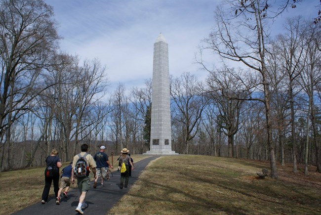 Group of visitors walk paved path to monument.