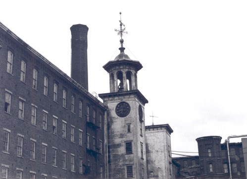 A mill tower and chimney, with the paint on the tower weathered
