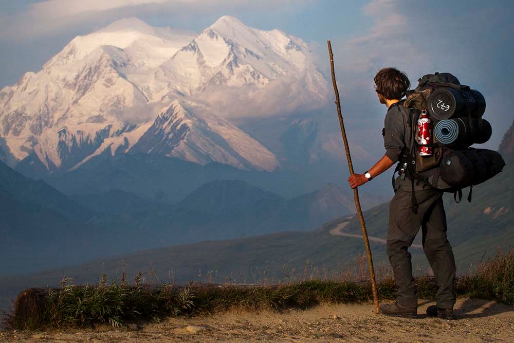 A backpacker looks out to view Denali.