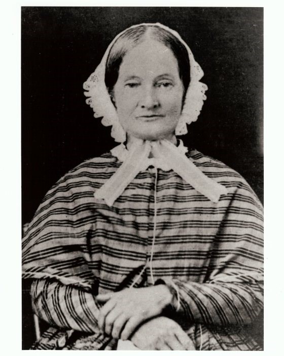 older woman wearing  dress sitting with her hands folded in her lap