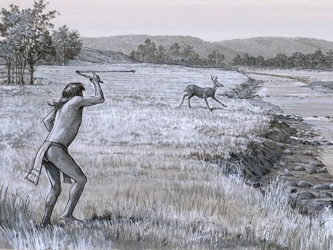 Dressed in a loincloth, the man holds the atlatl above his head. At one end balances the end of the spear, forming an elbow-shape.