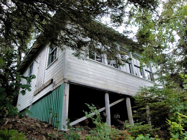 looking upslope at cottage, underbelly and many facing windows visible