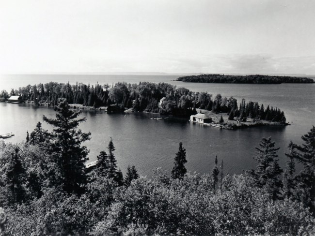 aerial view looking at an island, structures along shoreline, significant clearing at right tip