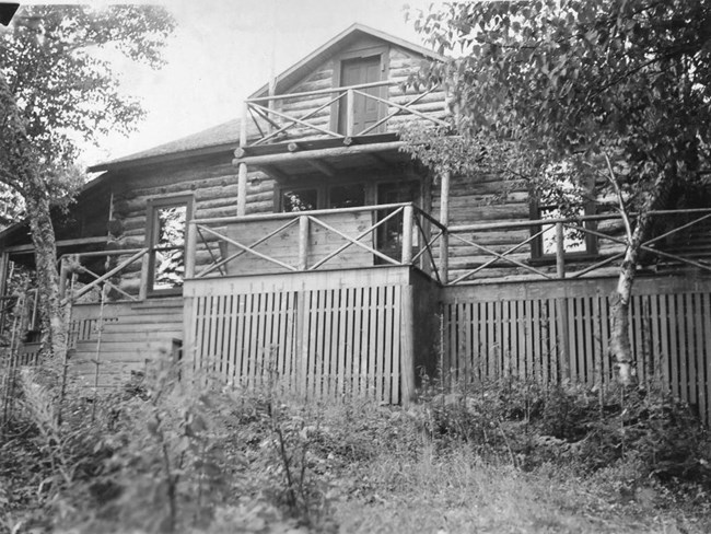 multi level log cabin with porches and log hewn railings encircling the structure