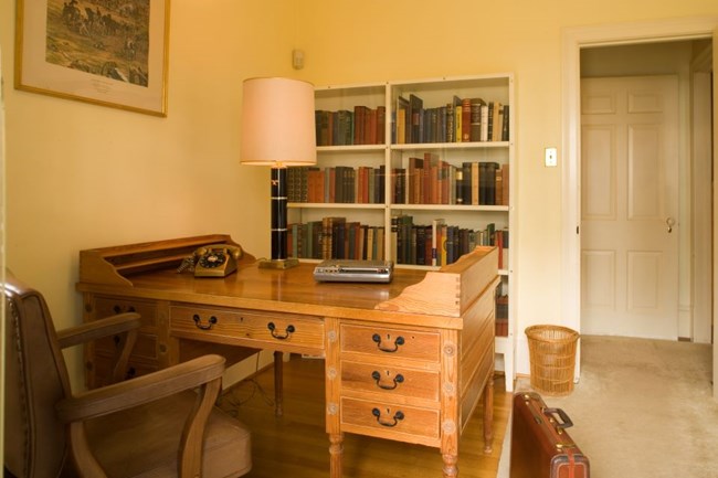 Color image of a wooden desk with a bookcase in the background