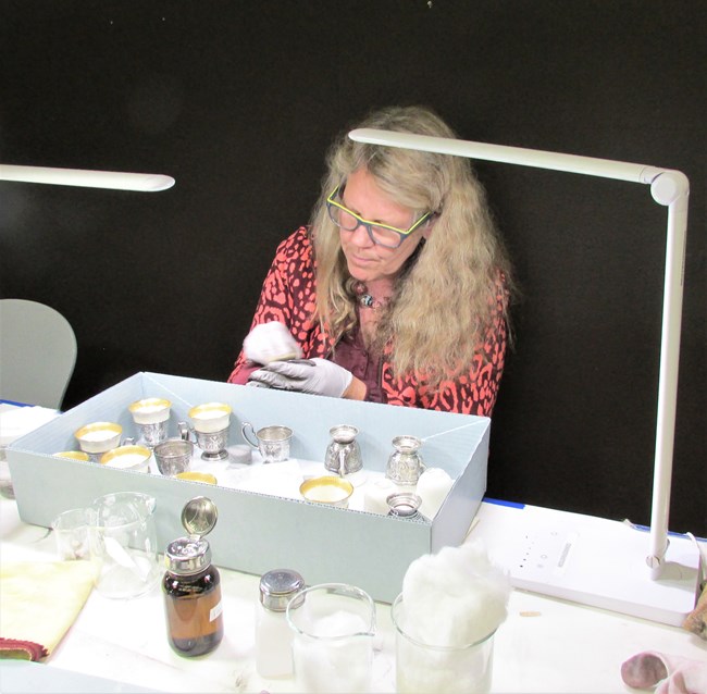 Ingrid Neuman cleaning silver tea cups.