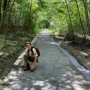 A young woman completes trail work while wearing an AmeriCorps shirt. 