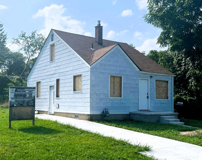 Blue house with boarded up windows