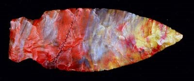 A brightly colored flaked and narrow arrowhead in bright colors of reds, blues, yellows and oranges.