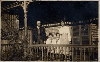 Two adults and two children standing on the porch of a house