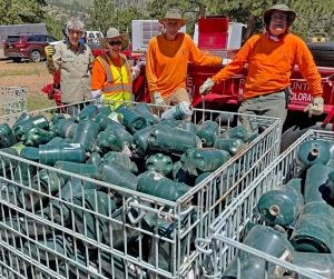 A group of volunteers are pictured by crates of propane cans.