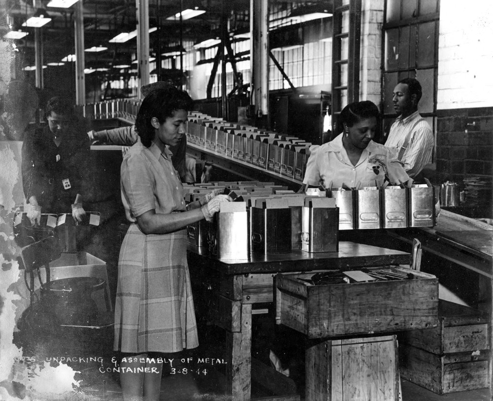 Black and white photo of Black women along an assembly line with metal items