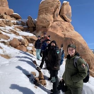 A group of volunteers in cold weather clothing are pictured with park staff in snowy, mountainous terrain.