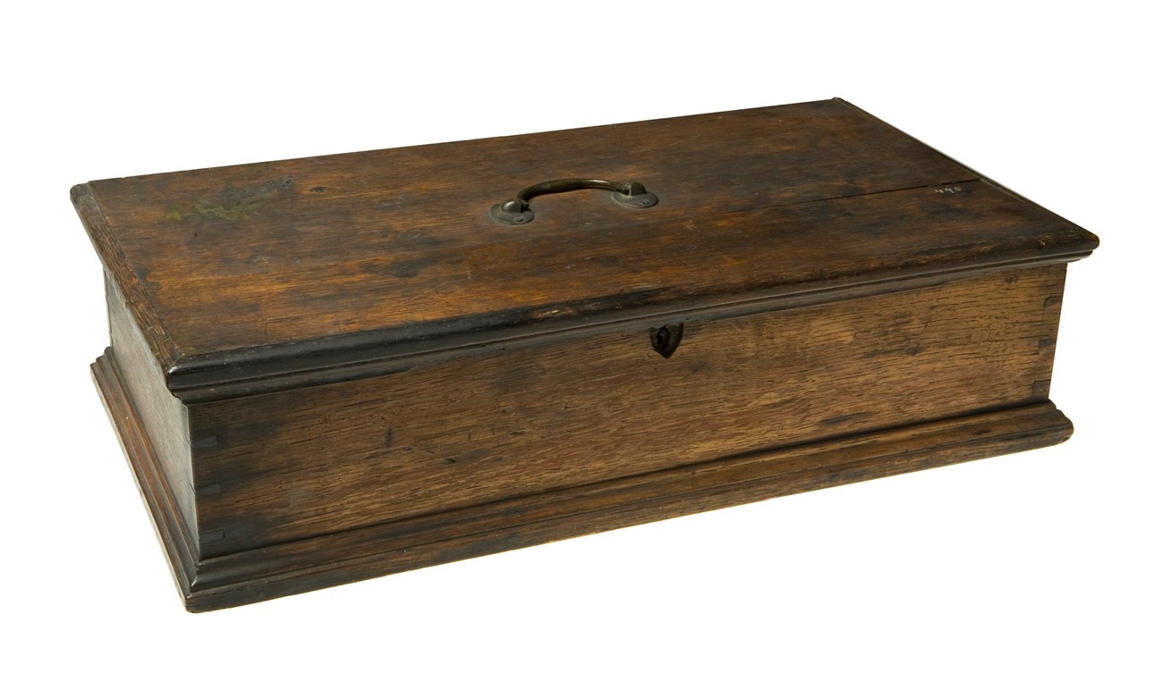 Rectangular oak cash box with small handle on top.