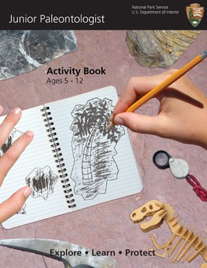 An image showing an open notebook and two hands drawing a fossil with a pencil