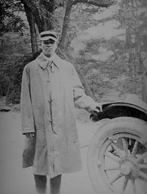 black and white image of James Fisher standing beside a car