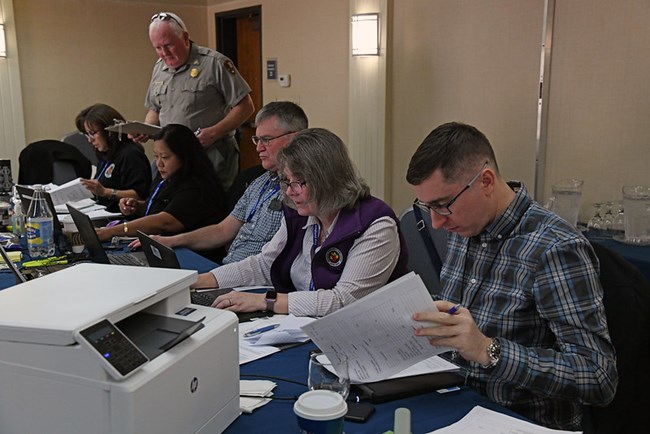 Employees handling applicant paperwork and entering data on computers.