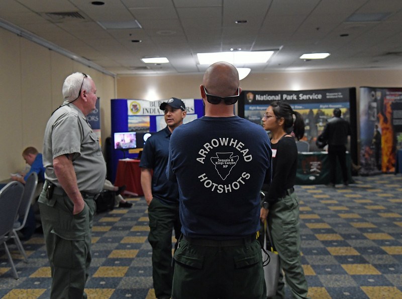 Three employees talk with a potential candidate at a job fair.