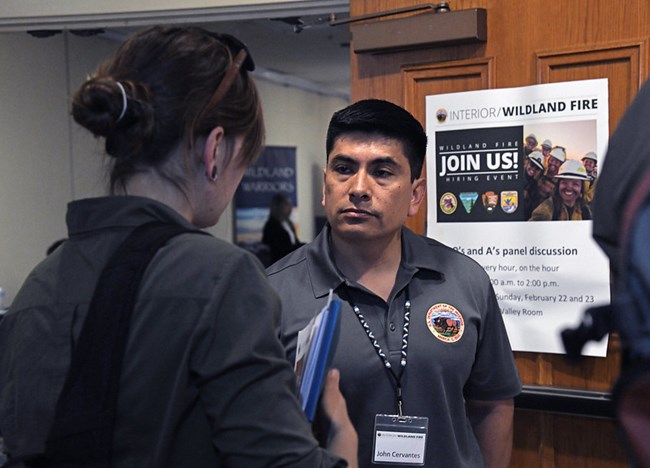 A potential wildland fire job candidates talks to a hiring official at a job fair.