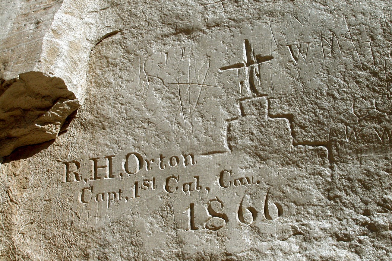 Photo of writing and drawing scratched into a rock surface