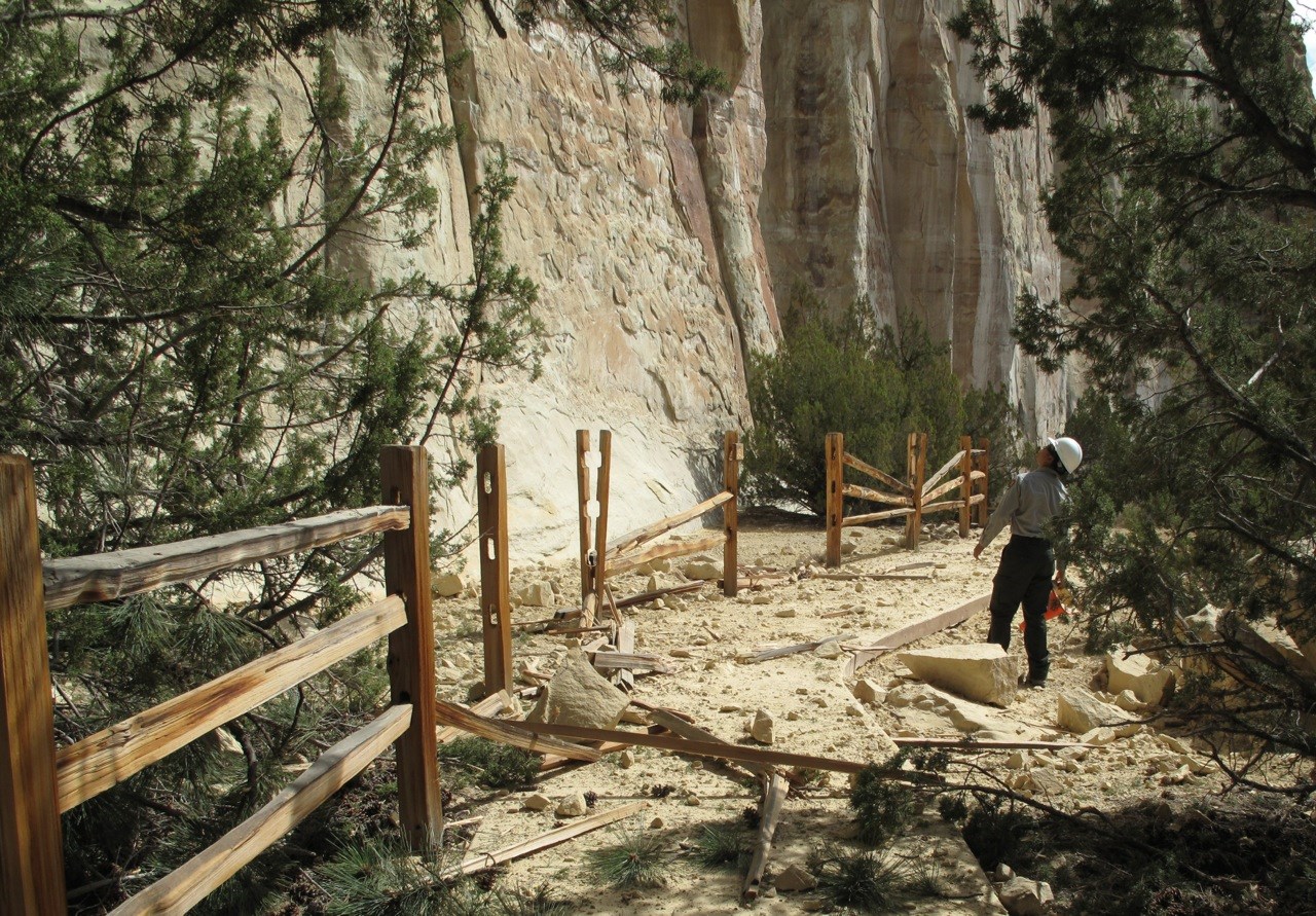 Photo of a trail with a broken fence and rock debris