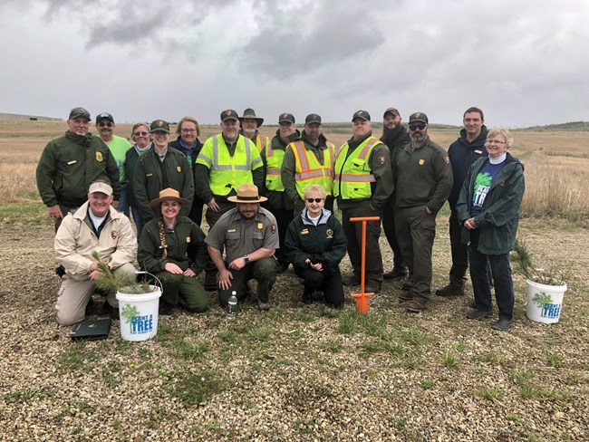 Volunteers and park staff pose with shovels and tree saplings