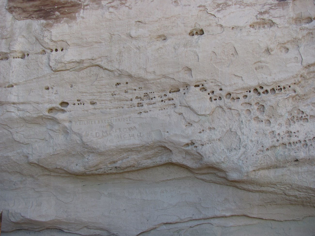 Photo of a sandstone surface with rows of small holes