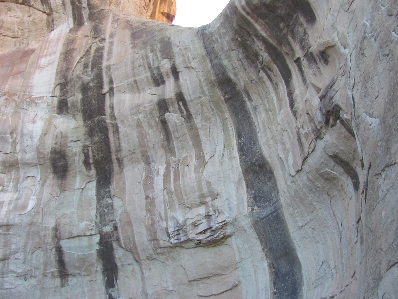 Photo of rock cliff with dark vertical stains