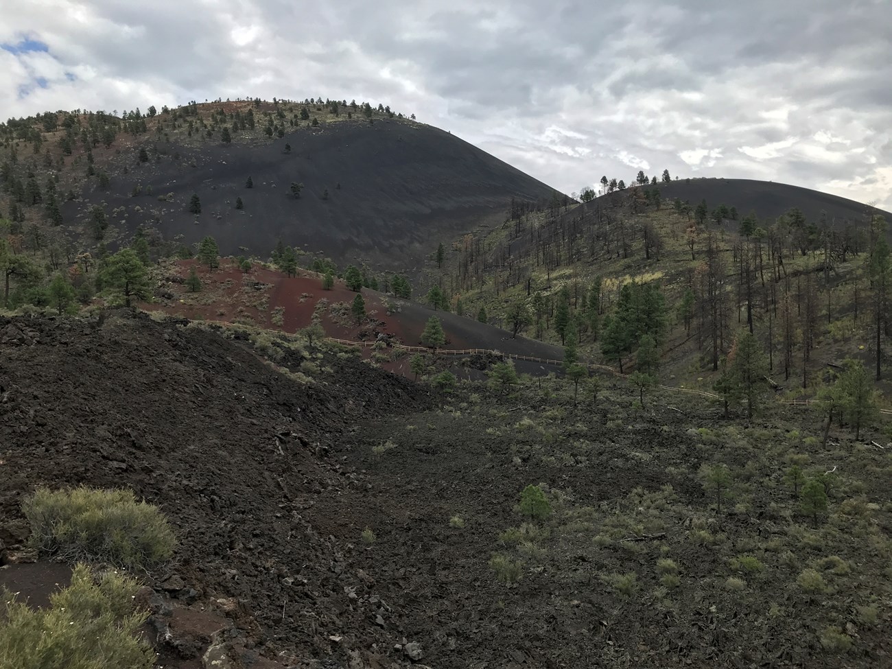 Photo of rounded volcanic peaks with lava flows in the foreground