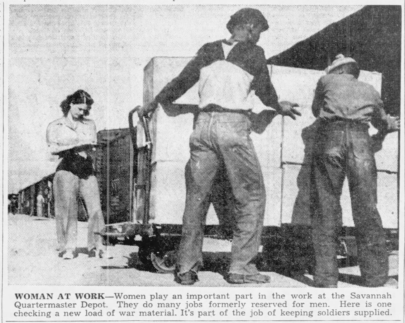 Black and white photo of a white woman with a clipboard and two African American men moving materials