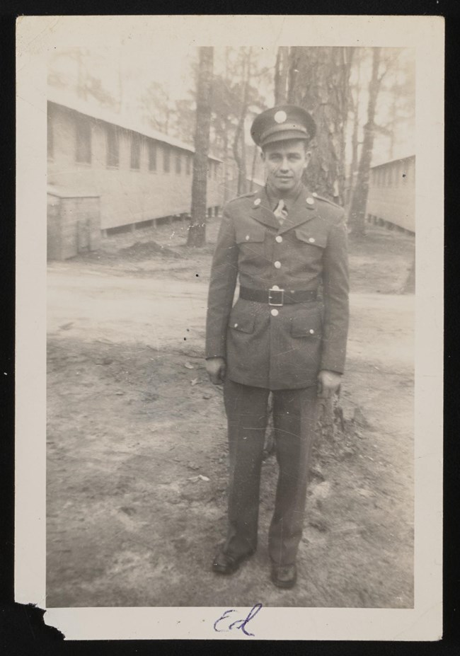 black and white photo of man in a uniform standing outside