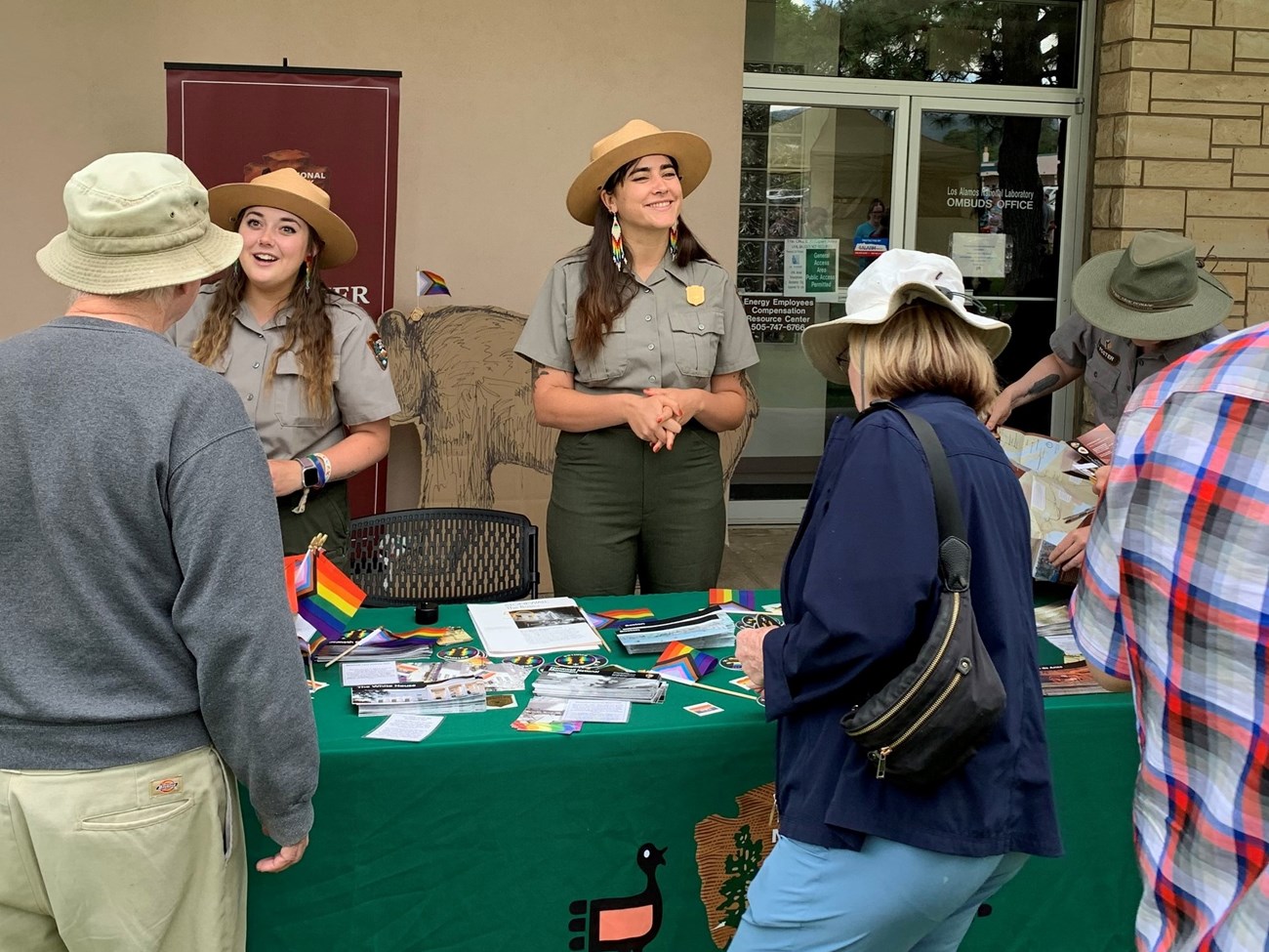 Two female park rangers talk to visitors.