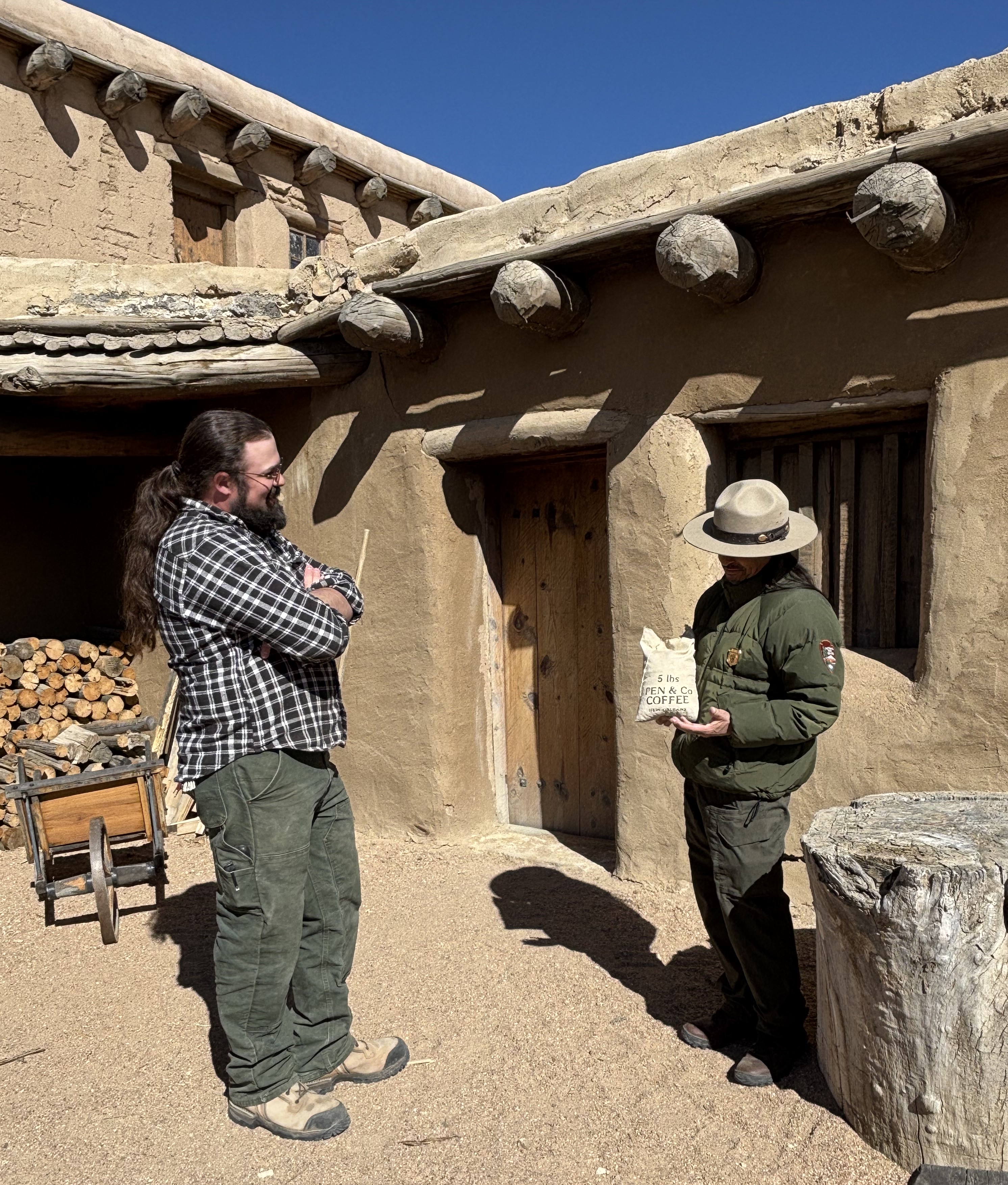 A park ranger holds a replica trade item while conversing with a visitor