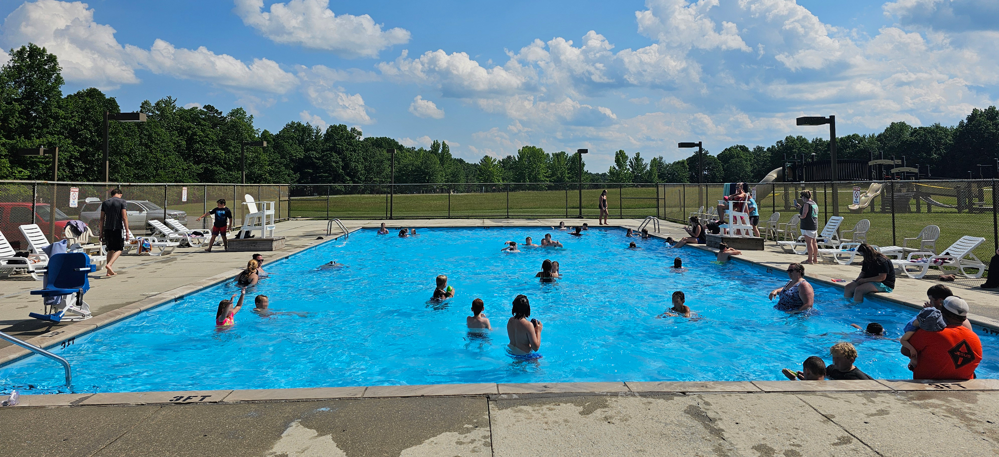 A group of people swimming in a pool on a sunny day.
