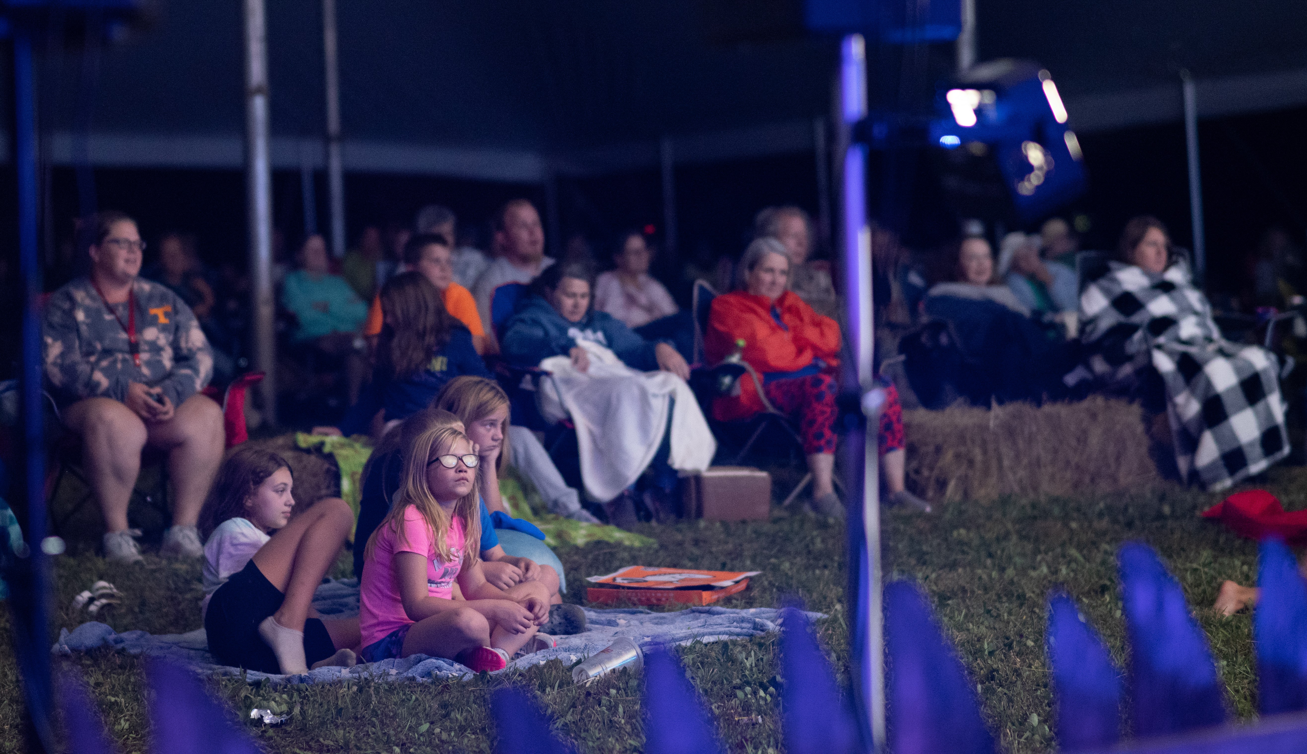 A crowd sitting under the big tent at night listening to storytellers.