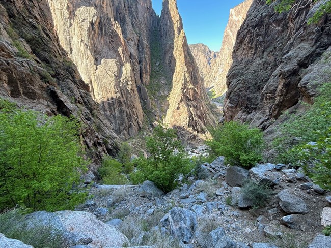 A view of a scree field leading down to a river between canyon walls