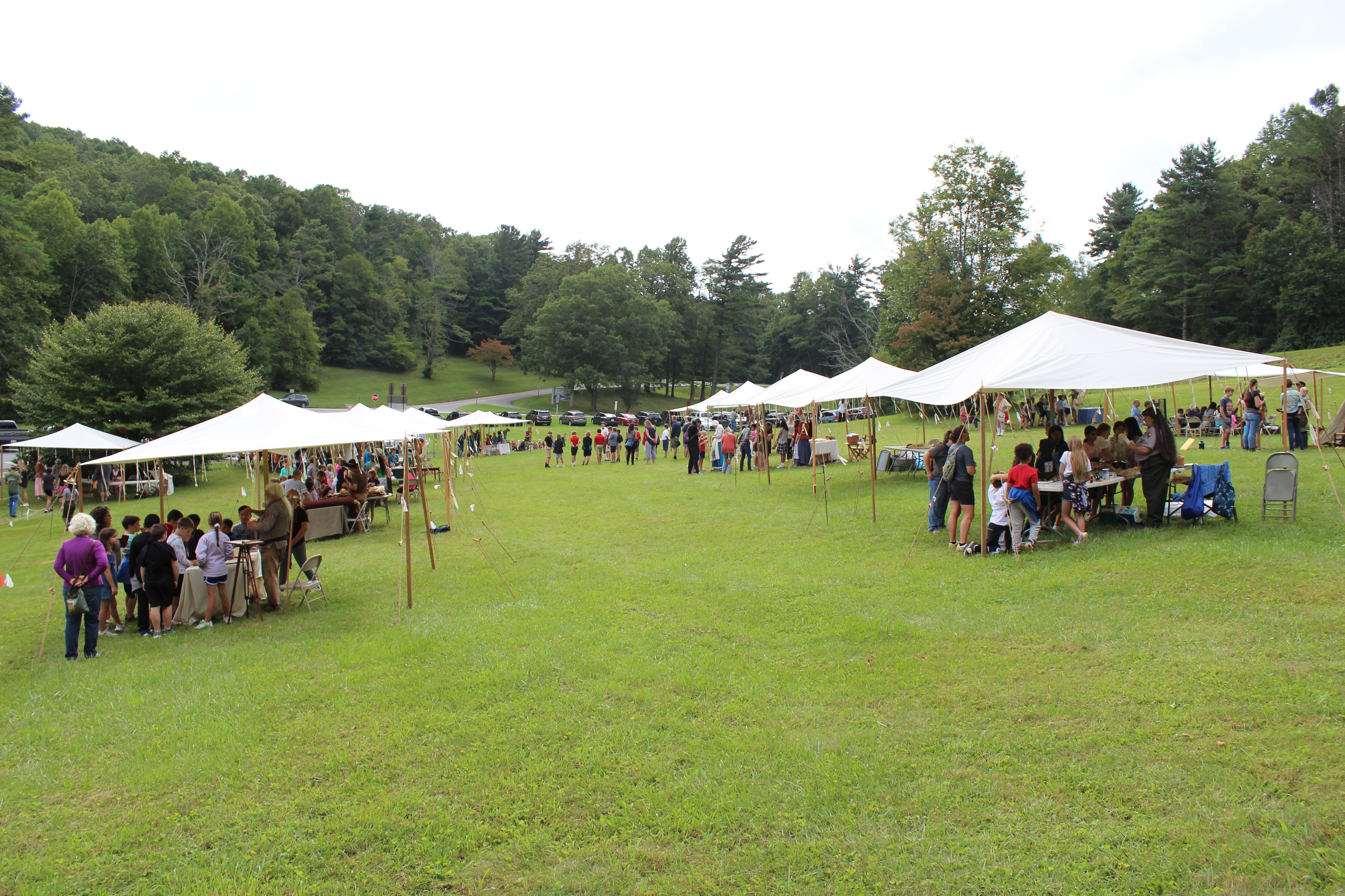 White tents in field with guests.
