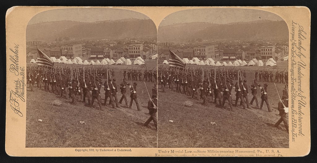 soldiers marching in uniform holding guns with bayonets and carrying the American flag