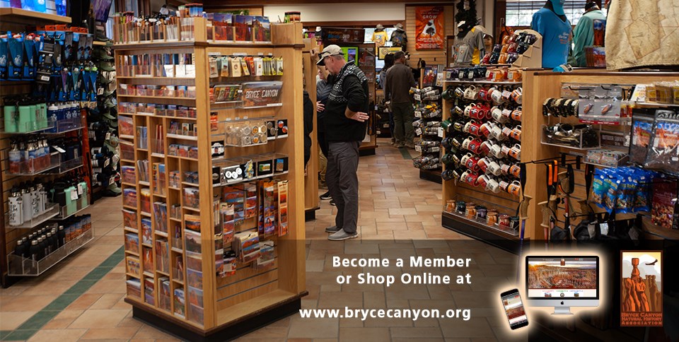 Two adults browse in a park gift shop stocked with many products; at the bottom a darkened banner invites you to become a member or shop online at www.brycecanyon.org