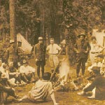 Black and white photo depicting an early camping experience with campers gathered around a campfire at Bryce Canyon