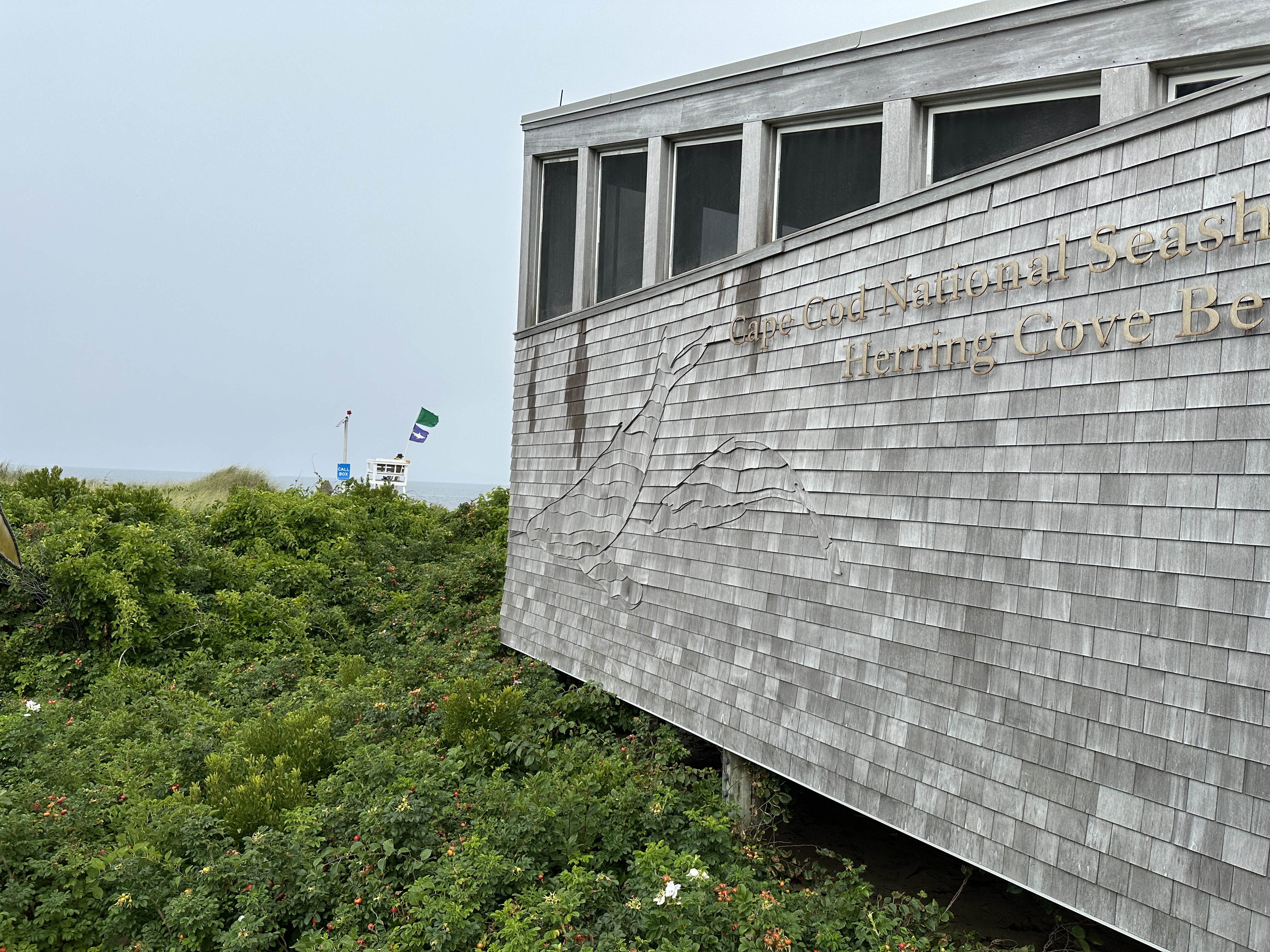 Gray shingled building looking out onto beach and ocean.