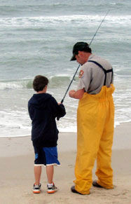 A ranger helps a young visitor to bait their hook for surf fishing.