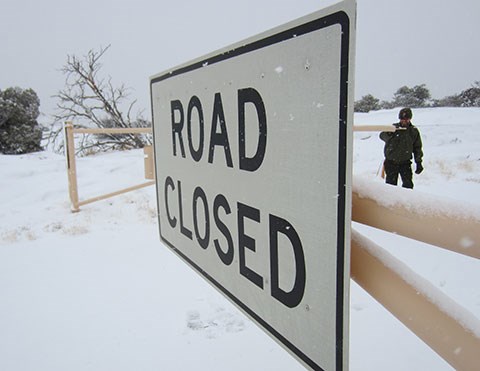 A road closed sign with snow in the background